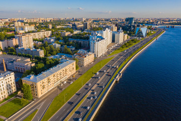 Fototapeta premium Panorama of Petersburg on a summer day. Top view of Petersburg. Rivers Of St. Petersburg. Blue water in Neva. Malookhtinsky Prospekt. Residential and office buildings on the Neva river. Trip to Russia