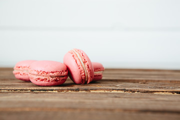 Sweet colorful French macaroon cookies dessert on brown wooden table over white wooden background