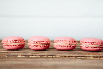 Sweet colorful French macaroon cookies dessert on brown wooden table over white wooden background