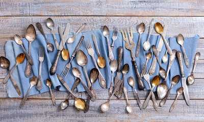 Vintage cutlery - spoons, forks and knives on an old wooden background.