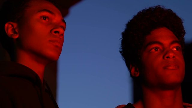 Two Afro-American male hooligans watching burning building at night, fire, crime