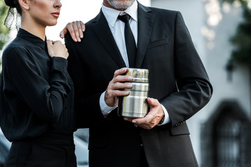 cropped view of woman standing near bearded man holding cemetery urn