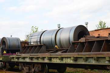Rolled steel coil on on a freight train fixed by a chain. Import/export, logistics of the heavy cargo multimodal transportation by rail. Customs control zone on railway, background