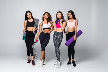 Fototapeta premium Four beauty women fitness holding different exercises equipment isolated on white background