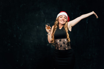 Christmas, celebration party, holiday, fun. Happy young woman celebrating New Year. Attractive smiling lady in Santa cap drinking champagne