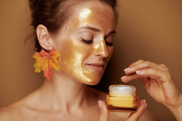 young woman with golden mask using cosmetic product