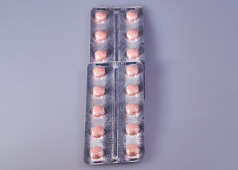 Plastic packaging with multi-colored pills on a gray background