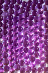 Abstract background of purple gel balls on a wet white surface