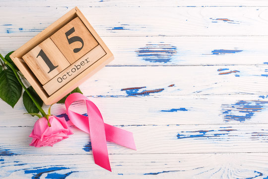 Pink ribbon, rose and wooden cube calendar set for October 15 on a wooden table. Breast Cancer Awareness Month