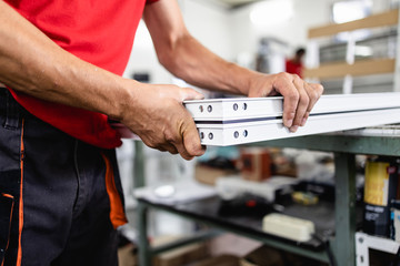 Manual worker assembling PVC doors and windows. Manufacturing jobs. Selective focus. Factory for aluminum and PVC windows and doors production.