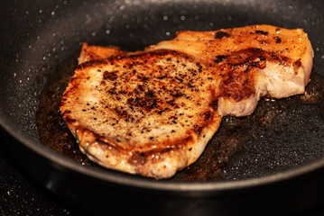 Pork chop is fried in a pan
