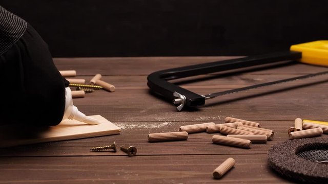 Tools on the wooden desk in workshop. Someone's hands are placing white glue on wooden plank. Nobody in the shot. 4k. Carpentry or engineering concept.