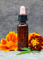 Marigold essential oil and fresh Tagetes flowers on old wooden background. Alternative medicine,aromatherapy or spa concept.Copy space.Selective focus.