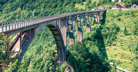 Sunny morning view of Djurdjevica bridge over the river Tara. Colorful summer morning in Montenegro, Europe. Beautiful world of Mediterranean countries. Traveling concept background.