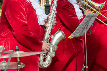 Saxophonist in a red suit close-up. Concept: playing the saxophone, music. Saxophone jazz music...