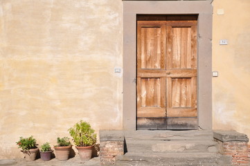 mediterrane Haustür aus Holz, daneben Terrakottatöpfe mit Pflanzen 