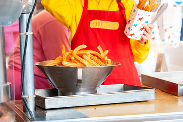 seller and cook sells churros in a cafe on the street