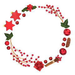 Abstract Christmas wreath decoration with red baubles, berry sprays, holly and winter flora on white background with copy space. Decorative symbol for the festive season.