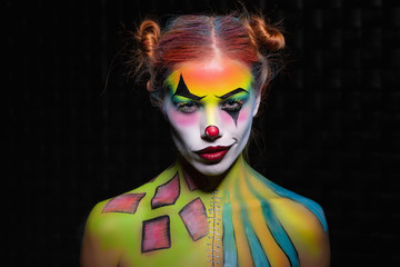 Sexy young woman with a face painting clown.