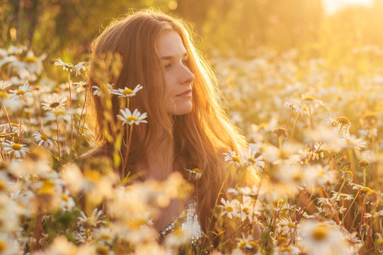 Side Portrait Of Pretty Blond Woman Sitting In Chamomile Field