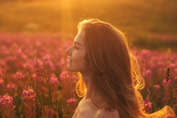 Side portrait of girl staying among blooming Sally field