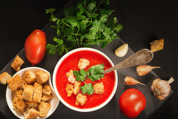 Tomato soup with garlic, crackers and parsley on a wooden table