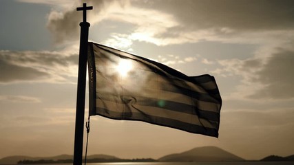 The flag of Greece flying in the wind on a ship sailing on the sea at dusk. 4K