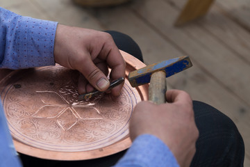 the man making pattern on the copper plate