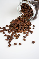 Ziarna kawy wysypujące się ze słoika, białe tlo