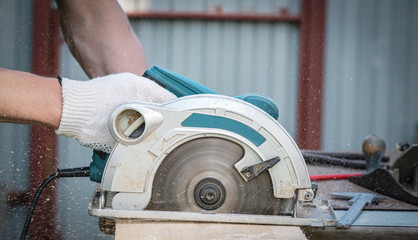 Man is cutting a wooden bar by a circular saw. Woodwork.