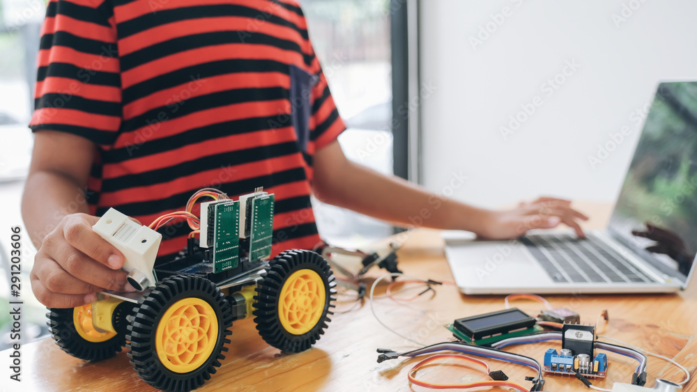 Wall mural boy with tablet pc computer programming electric toys and building robots.