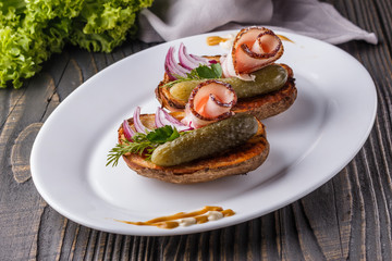 Halves baked potato with pickled cucumber, dill, salo and onion on wooden table