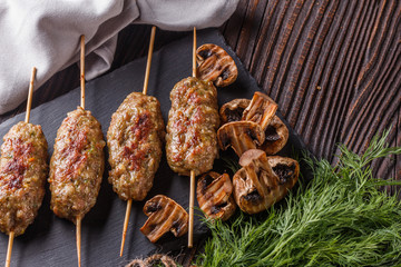 Shish kebab on the skewers with grilled mushrooms on rustic table
