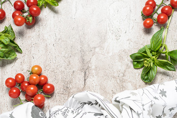 Marble textured background decorated with bright red cherry tomatoes, fresh green basil and white...