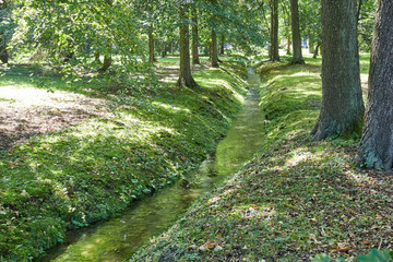 Obraz premium Wide canal with stone shores and a park on the shore