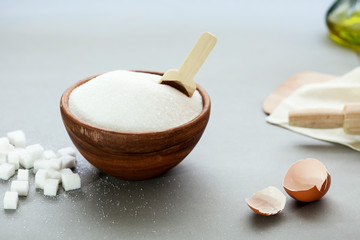 Fototapeta na wymiar sugar in bowl and spoon on gray background