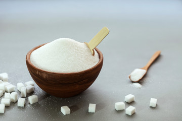 Fototapeta na wymiar sugar in bowl and spoon on gray background