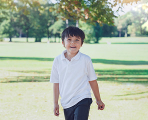 Portrait of happy school kid playing in the park, Child having fun playing outside in sunny day Autumn,  Little boy relaxing outdoor after school. Positive children concept