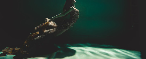 young woman swimming alone with fashion fabric underwater incognito