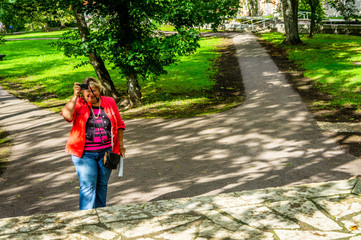 Obraz premium Mature woman in red jacket is resting in the Park by the river.