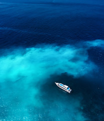 Fast boat at the sea in Bali, Indonesia. Aerial view of luxury floating boat on transparent blue...