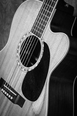 Beautiful grayscale shot of an acoustic guitar leaned on a wooden door on a wooden surface