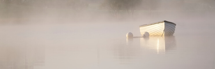 Dreamy boat scene banner in fog and golden sun for tranquility calm peace and mindfulness yoga