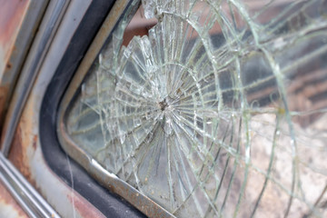 Broken glass window of an old rusty car