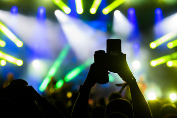 People taking photographs with smart phone during a public music concert with can of beer in hand
