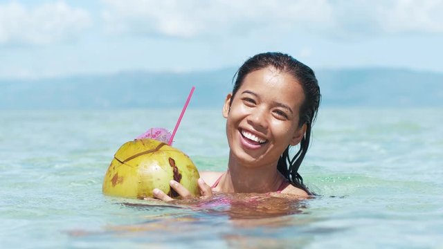 Close up shot of a happy woman drinking coconut in a relaxing vacation on island
