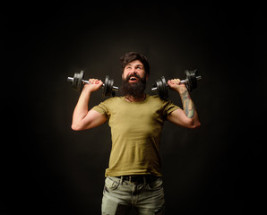 Fototapeta na wymiar Fitness model with dumbbells.. Athletic man doing exercise with dumbbells. Strength and motivation. Handsome man lifting dumbbells at gym. Strong athletic man. Sporty man with dumbbells. Athletic guy.