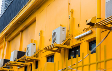 Modern air conditioner on a yellow wall. Air conditioning compressor   with black glass windows on the yellow wall building background.