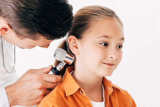 focused pediatrist in white coat examining child with dermascope isolated on white