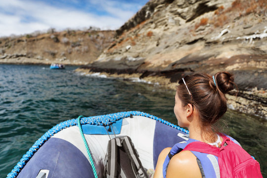 Galapagos tourist woman riding on panga zodiac boat tour in the Galapagos island, cruise travel vacation. Asian girl having fun.